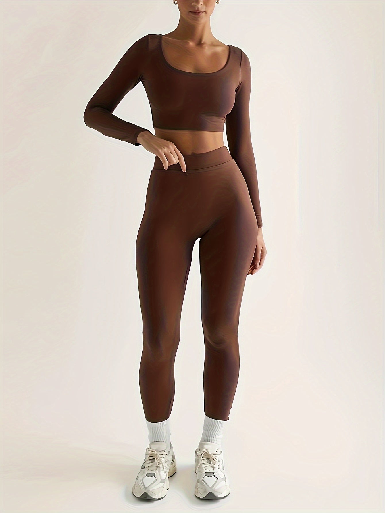 Sportset bestaande uit een crop-top met lange mouwen en een skinny broek met hoge taille