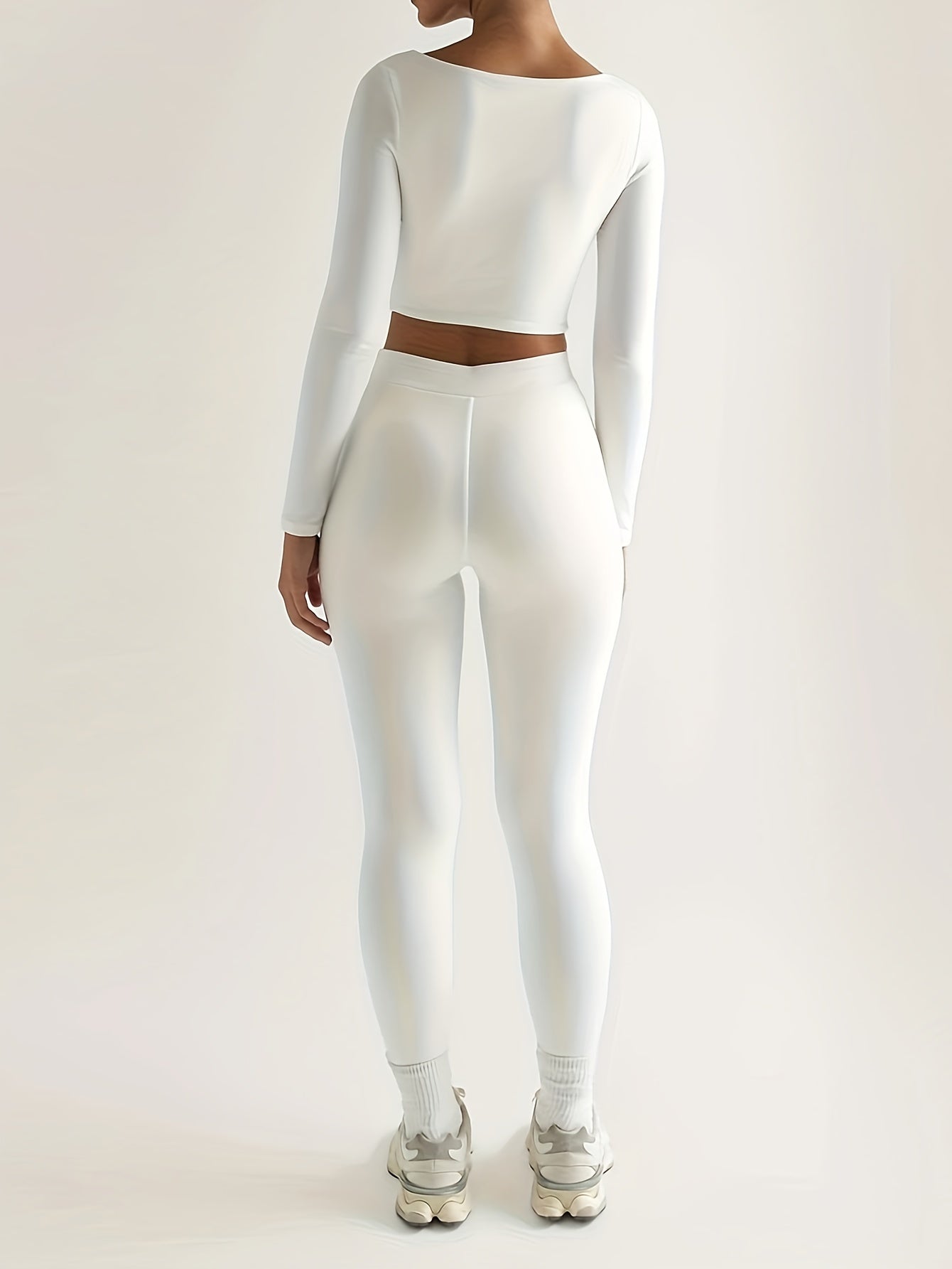 Sportset bestaande uit een crop-top met lange mouwen en een skinny broek met hoge taille