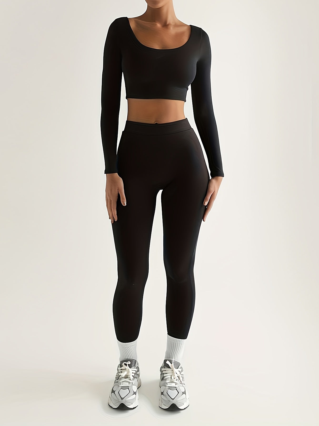 Sportset bestaande uit een crop-top met lange mouwen en een skinny broek met hoge taille