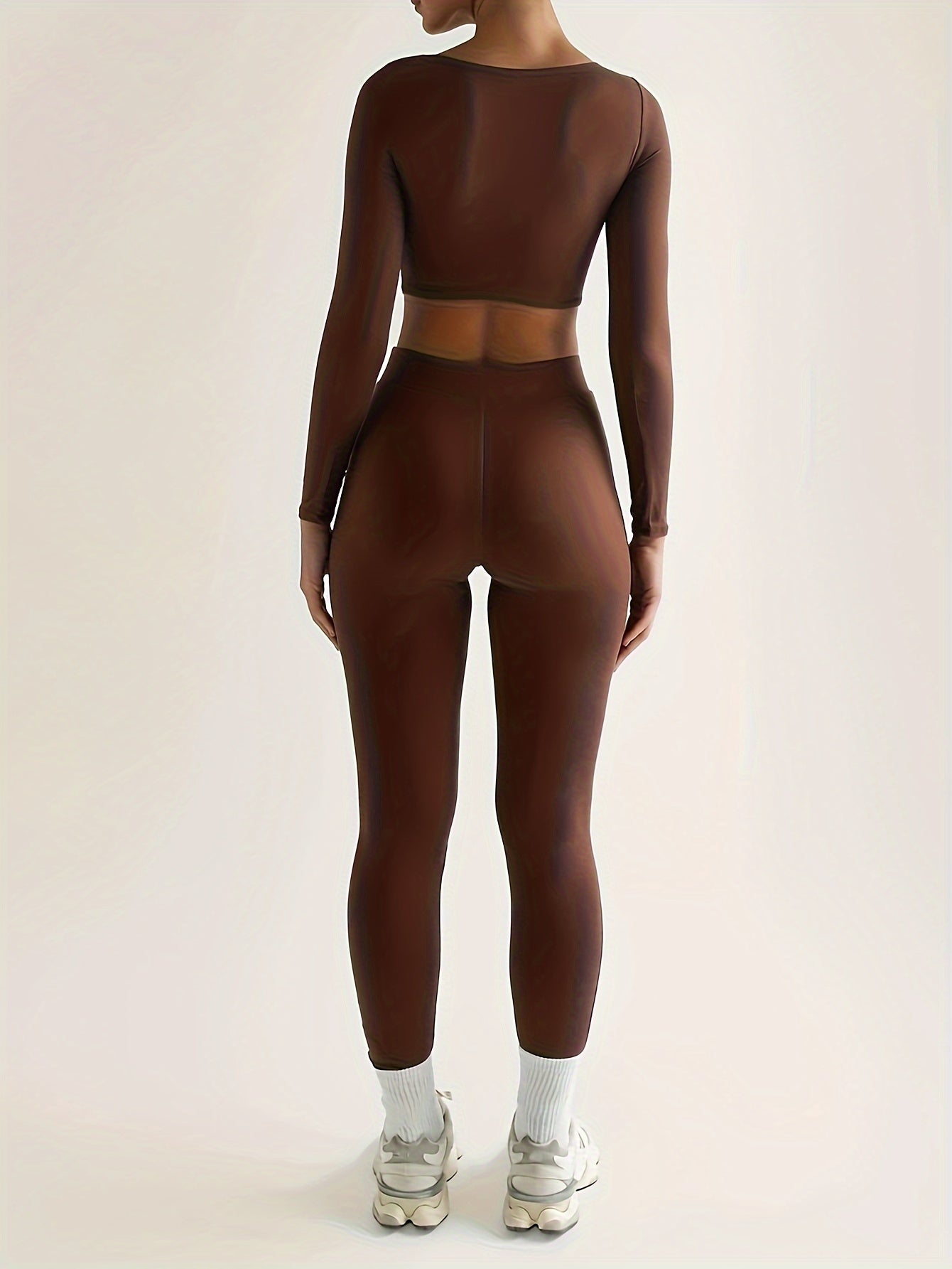 Sportset bestaande uit een crop-top met lange mouwen en een skinny broek met hoge taille