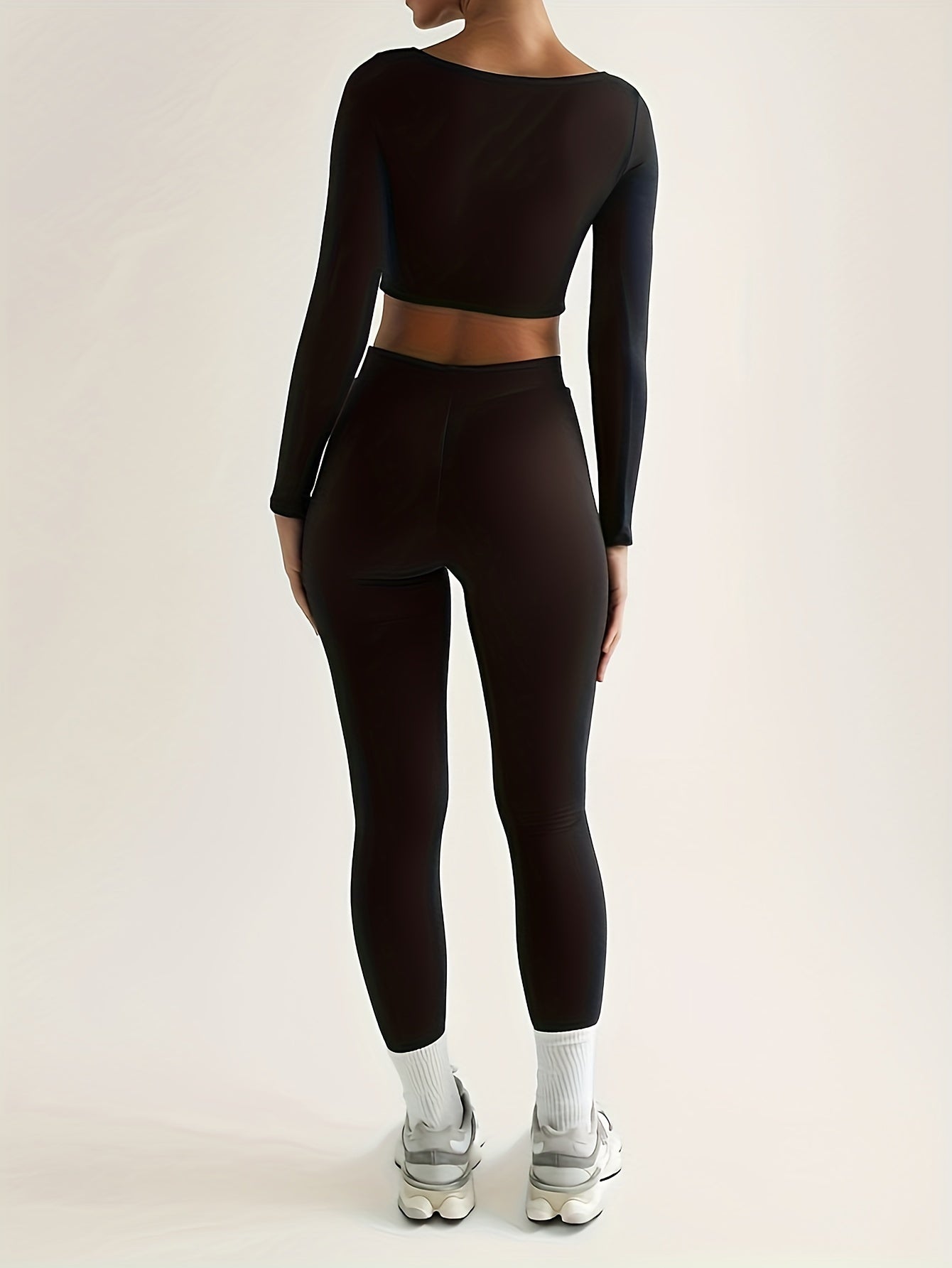 Sportset bestaande uit een crop-top met lange mouwen en een skinny broek met hoge taille